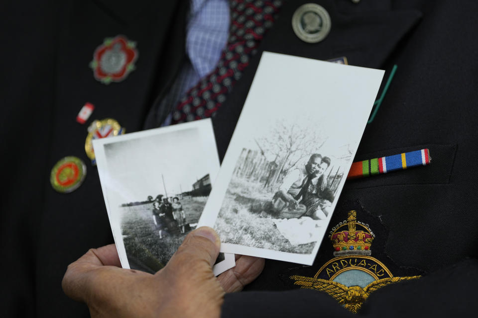 Gilbert Clarke a D-Day veteran holds up old photographs of himself as he is interviewed near his home in east London, Wednesday, May 15, 2024. Clarke, now 98, is one of more than 3 million men and women from South Asia, Africa and the Caribbean who served in the British military during World War II. (AP Photo/Kirsty Wigglesworth)