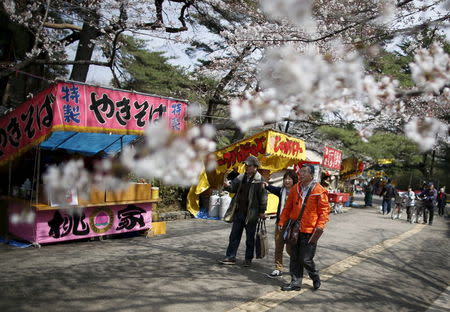 61-year-old Masahiko Sato (R), who has become a kind of "poster boy" for Japan's growing number of people with dementia, strolls with his supporters during a cherry blossom viewing event at Omiya park in Omiya, north of Tokyo, Japan, March 27, 2016. REUTERS/Issei Kato