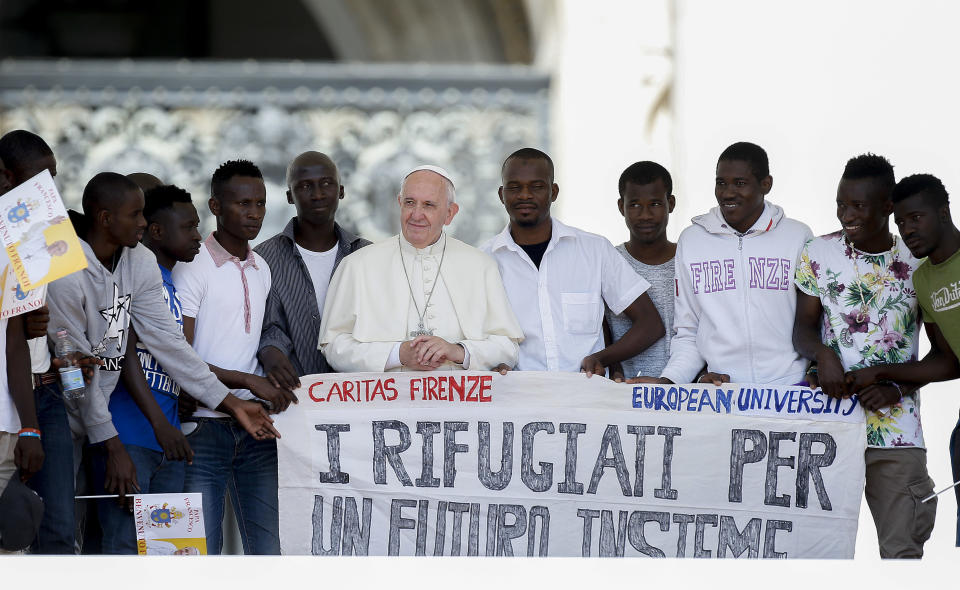 En esta imagen de archivo, el papa Francisco posa para una fotografía con un grupo de refugiados a los que invitó a las escaleras de la Basílica de San Pedro, con una bandera con la frase (en italiano) "Los refugiados para un futuro junto", durante su audiencia general semanal, en la Plaza de San Pedro, en el Vaticano, el 22 de junio de 2016. (AP Foto/Fabio Frustaci, archivo)