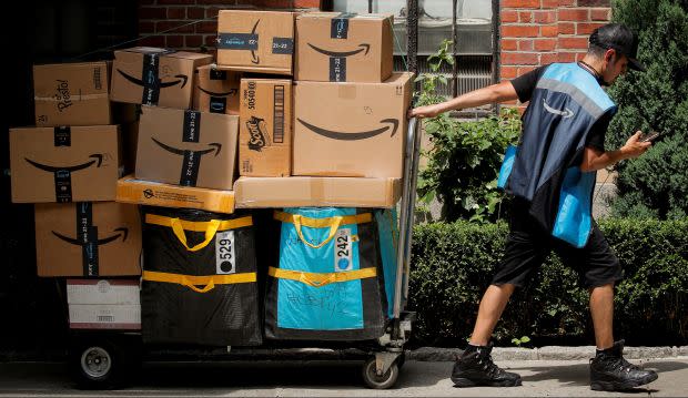 An Amazon delivery worker pulls a delivery cart full of packages