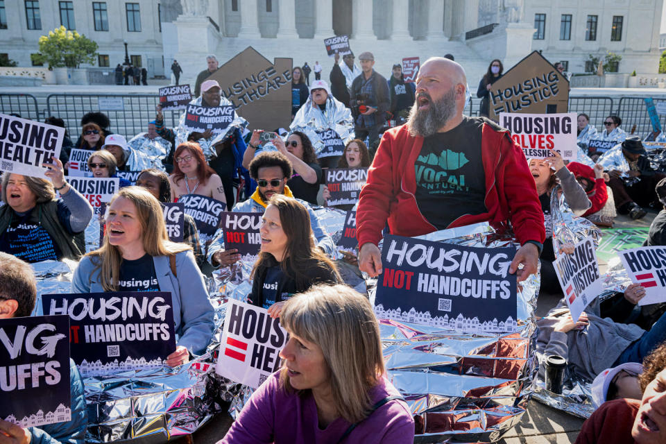 Demonstrators hold signs and use reflective blankets. (Saul Loeb / AFP via Getty Images)