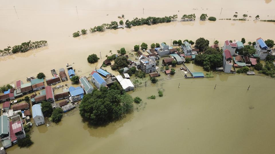 FILE - Floodwaters surround a village in Chuong My district, Hanoi, Vietnam on July 31, 2018. Far more people are in harm's way as they move into high flood zones across the globe, adding to an increase in watery disasters from climate change, a new study said. (AP Photo/Manh Thang, File)