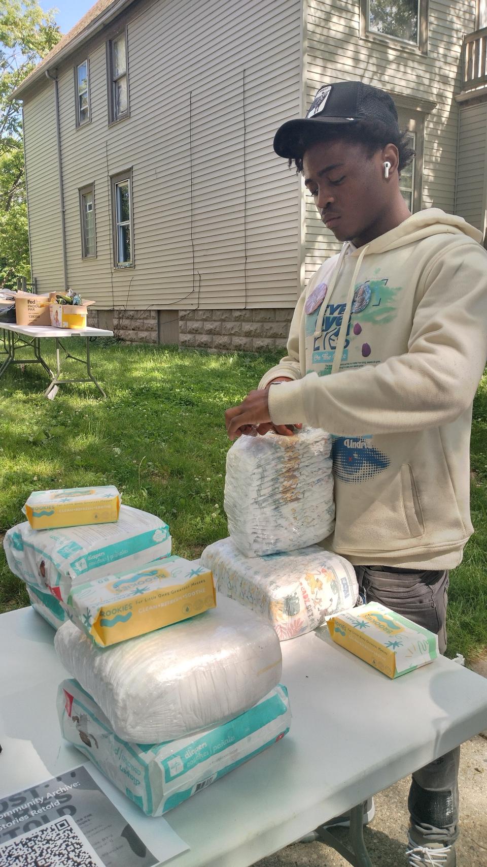 Metcalfe Park resident Zemarius Jones, 21, inspects diapers he picked at the mutual aid shed operated by Metcalfe Park Community Bridges. The neighborhood organization stocks donated items like diapers, wipes, clothes, hygiene products and health kits at the shed and distributes to residents for free.