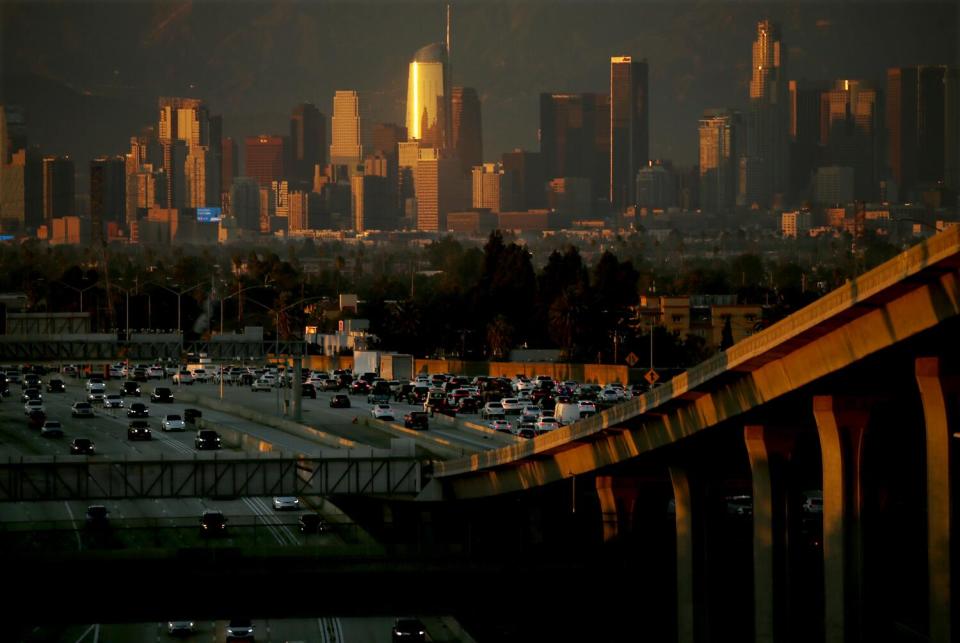 A smoggy sky, with the downtown Los Angeles skyline and a freeway packed with cars