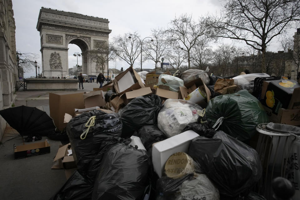 FILE - Uncollected garbage near the Arc de Triomphe in Paris, Wednesday, March 22, 2023. Unrest in France is tarnishing the sheen of King Charles III’s first overseas trip as monarch. Striking workers have refused to provide red carpets and critics are calling for the British king's visit to be canceled altogether amid pension reform protests. (AP Photo/Christophe Ena, File)