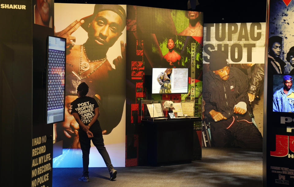 FILE - A visitor observes a display of late hip hop artist Tupac Shakur during the press preview day for the "Tupac Shakur. Wake Me When I'm Free" exhibition, Thursday, Jan. 20, 2022, at The Canvas at L.A. Live in Los Angeles. The unsolved killing of Shakur has taken a major turn. Duane “Keffe D” Davis was arrested Friday morning, although the exact charge or charges were not immediately clear, according to two officials with first-hand knowledge of the arrest. The renewed activity comes nearly 30 years after Shakur was gunned down on Sept. 7, 1996. (AP Photo/Chris Pizzello, File)