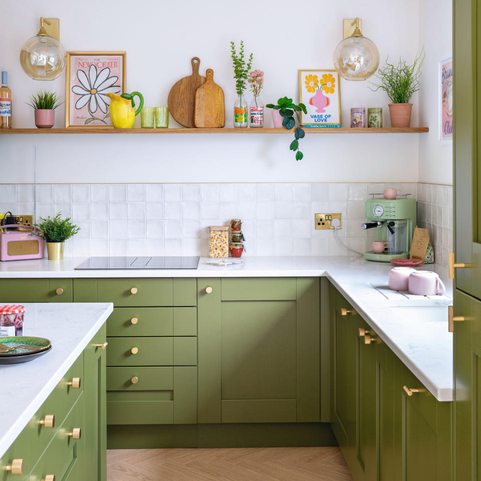  White painted and tiled kitchen with green painted kitchen cabinets and drawers with gold hardware. 