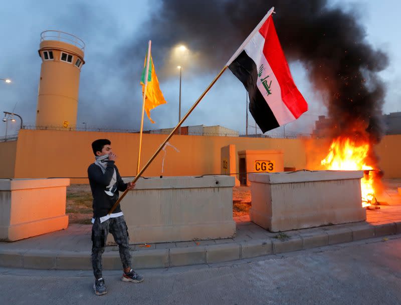 A protester holds an Iraqi flag during a protest to condemn air strikes on bases belonging to Hashd al-Shaabi (paramilitary forces), outside the main gate of the U.S. Embassy in Baghdad