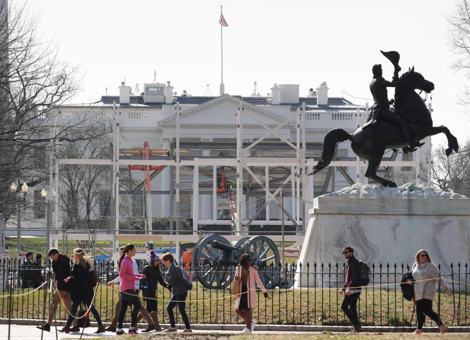 In this photo taken Feb. 17, 2017, pedestrians walk through Lafayette Park, across from the White House in Washington, as work continues with the dismantling of the presidential inauguration reviewing stand. (AP Photo/Pablo Martinez Monsivais)