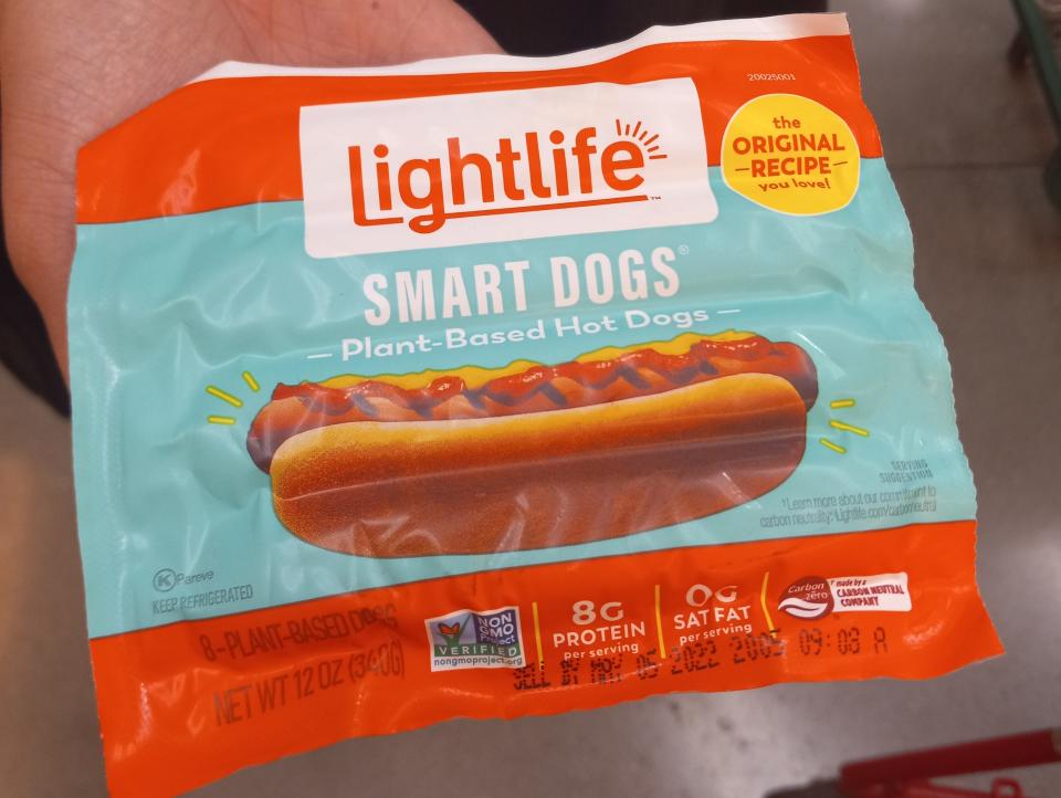hand holding package of lightlife plant based hot dogs at trader joes