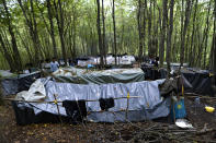 Migrants walk between improvised tents at a makeshift camp in a forest outside Velika Kladusa, Bosnia, Friday, Sept. 25, 2020. Remote woods, abandoned run-down buildings and roadsides on the fringes of northwestern Bosnian towns are steadily filling with makeshift camps where migrants from the Middle East, Asia and North Africa are bracing for more misery as autumn's chill and rains set it. (AP Photo/Kemal Softic)