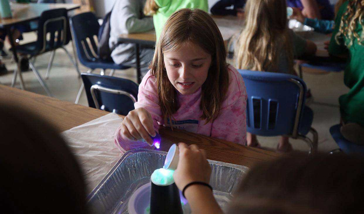 Ellie Bills, 10,  holds the glow light as she and her team watch the ice volcano bubble up June 9 during the Spacecation portion of Grandview's Camp Invention program, which was June 6-10 at Edison Intermediate Larson Middle School. The project was used to give the campers an idea of the ice volcanos on Europa, one of Jupiter's moons.