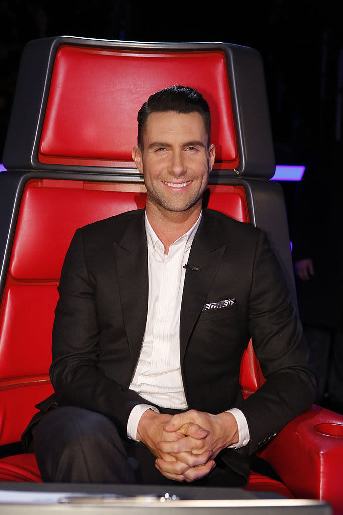 Adam smiles as he sits in the judge's chair on the voice