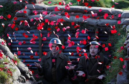 Actors Jake Morgan and Sam Ducane extend their hands to catch poppies, as they pose for photographs at the launch of the 1918 Poppy Pledge in a re-creation of a First World War trench at Pollock House in Glasgow, Scotland November 10, 2017. The actors appeared in the The Wipers Times, a play named after a magazine published by British soldiers in the First World War. REUTERS/Russell Cheyne