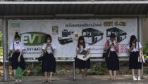 Students from Chulalongkorn University wear face masks to protect themselves from poor air quality as they wait at a bus stop in Bangkok, Thailand, Monday, Jan. 20, 2020. Thick haze blanketed the Thai capital on Monday sending air pollution levels soaring to 89 micrograms per cubic meter of PM2.5 particles in some areas, according to the Pollution Control Department. (AP Photo/Sakchai Lalit)