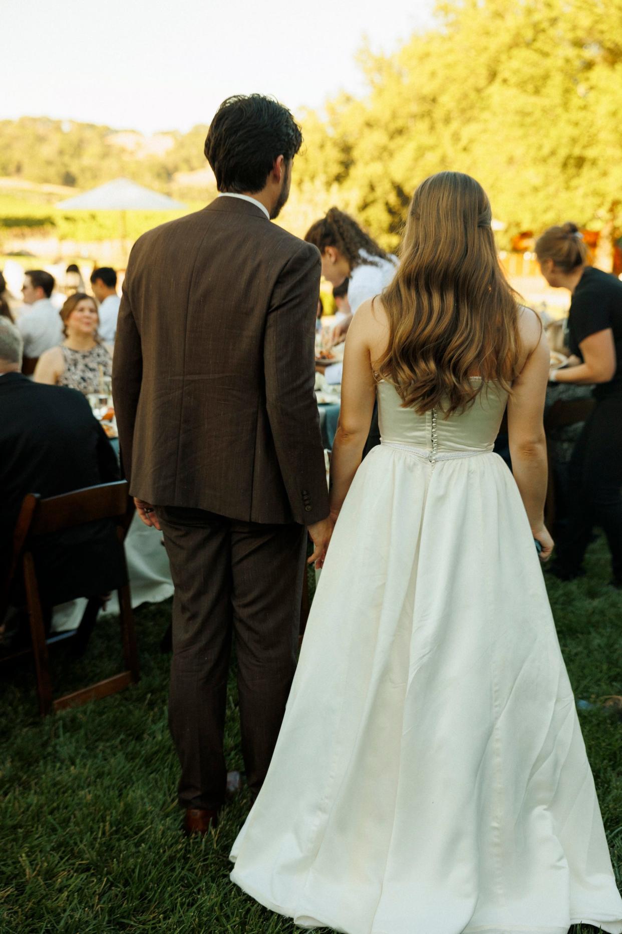 A bride and groom walk towards their wedding guests.