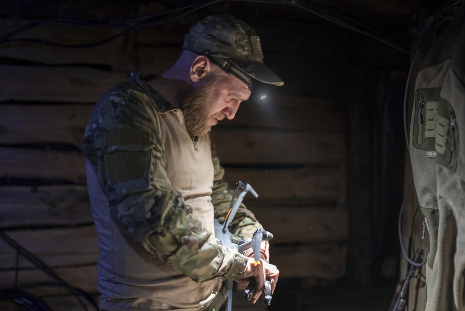 CORRECTS LOCATION TO BAKHMUT IN PHOTO DETAILS - A Ukrainian serviceman from Code 9.2 unit known by call sign Mamay attaches drop bomb to a drone in the trenches at the frontline, few kilometres from Bakhmut, Donetsk region, Ukraine, Tuesday, April 23, 2024. (AP Photo/Alex Babenko)