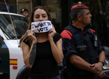 A protestor holds up a sign in front of a Catalan police outside the Catalan region's foreign affairs ministry building during a raid by Spanish police on government offices, in Barcelona, Spain, September 20, 2017. REUTERS/Susana Vera