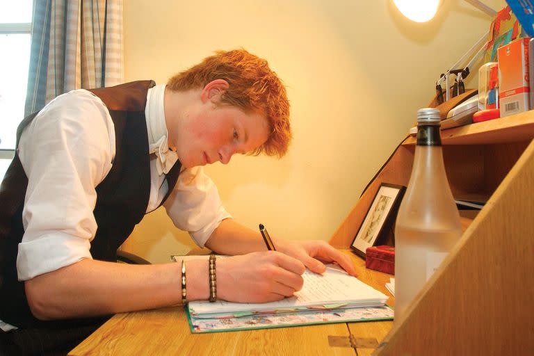 El príncipe Harry escribiendo en su escritorio en su habitación en el internado de Eton College