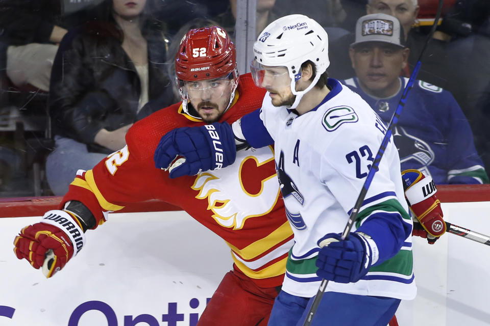 Vancouver Canucks' Oliver Ekman-Larsson, right, works against Calgary Flames' MacKenzie Weegar during the first period of an NHL hockey game Saturday, Dec. 31, 2022, in Calgary, Alberta. (Larry MacDougal/The Canadian Press via AP)