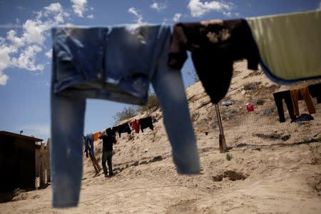 A Central American migrant hangs his clothes at the 'Aposento Alto' provisional shelter, on the outskirts of Ciudad Juarez
