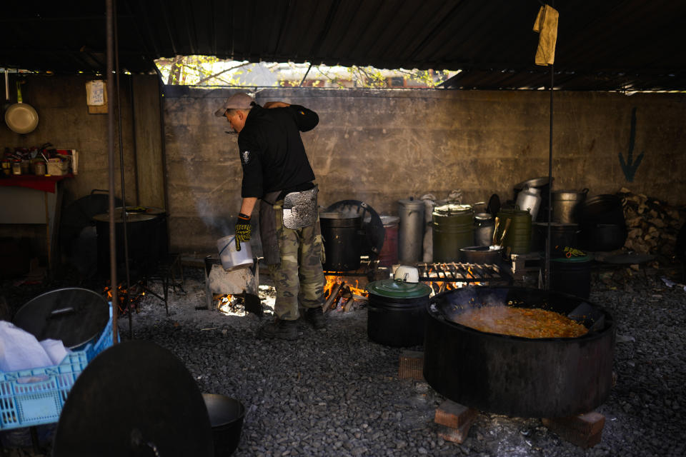 A volunteer cooks at a facility producing material for Ukrainian soldiers in Zaporizhzhia, Ukraine, Saturday, May 7, 2022. An old industrial complex in the southeastern Ukrainian riverside city of Zaporizhzhia has become a hive of activity for volunteers producing everything from body armor to camouflage nets, anti-tank obstacles to heating stoves and rifle slings for Ukrainian soldiers fighting the Russian invasion. (AP Photo/Francisco Seco)
