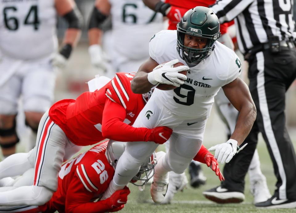 Michigan State Spartans running back Kenneth Walker III (9) is tackled by Ohio State Buckeyes safety Bryson Shaw (17) and cornerback Cameron Brown (26) during the first quarter of the NCAA football game at Ohio Stadium in Columbus on Saturday, Nov. 20, 2021. 