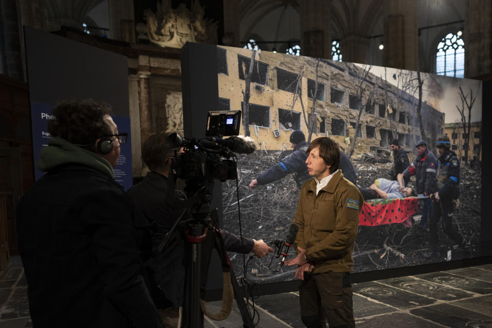 World Press Photo of the Year award winner, Associated Press photographer Evgeniy Maloletka, is interviewed in front of his winning image of a pregnant woman being carried through the wreckage of a maternity hospital after a Russian military strike in Mariupol, Ukraine, prior to a press conference announcing the winners in Amsterdam, Netherlands, Thursday, April 20, 2023. (AP Photo/Peter Dejong)