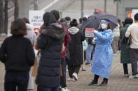 FILE - A medical worker holds a sign for visitors to prepare for the coronavirus tests at a temporary screening clinic for coronavirus in Seoul, South Korea on Dec. 10, 2021. Caseloads of omicron have remained relatively low in many countries in Asia. For now, many remain insulated from the worst, although the next few months will remain critical. (AP Photo/Lee Jin-man, File)