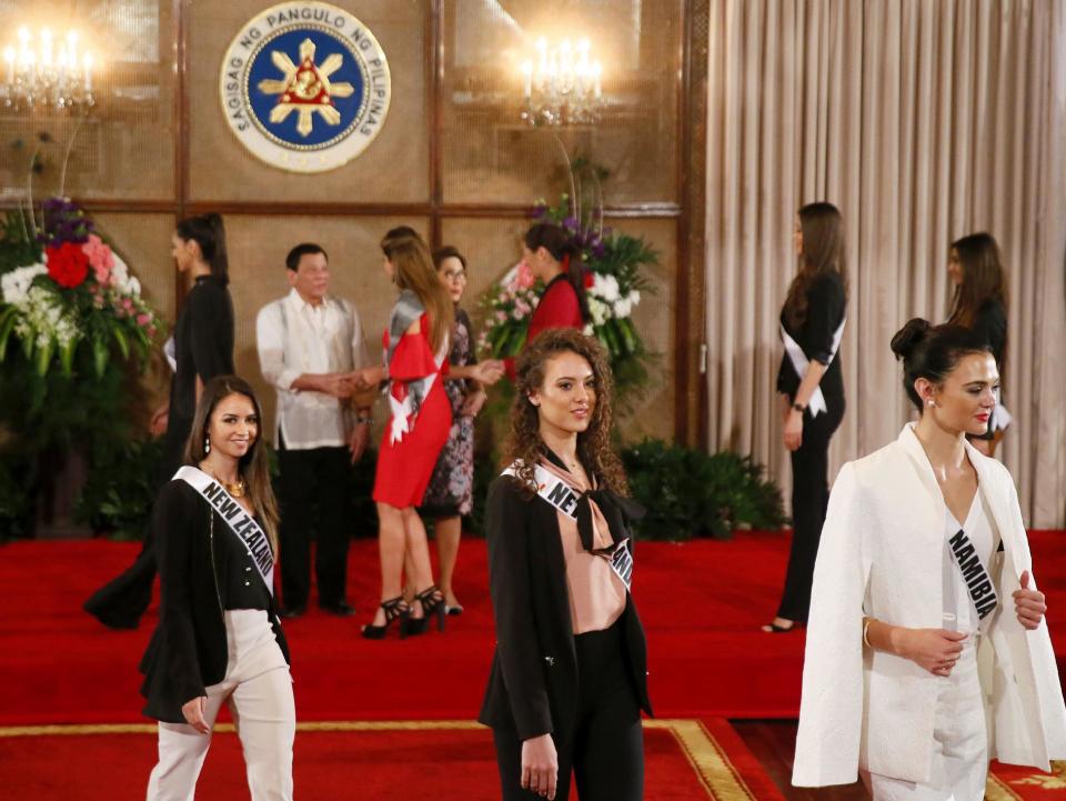 Las concursantes en el certamen de belleza Miss Universo (desde la izquieda, en el fondo), Tania Dawson de NUeva Zelanda; Zoey Ivory de Holanda y Lizelle Esterhuizen de Namibia, regresan a sus sitios tras saludar al presidente de Filipinas, Rodrigo Duterte (segundo por la izquierda en el fondo de la sala), durante una visita de cortesía al palacio presidencial de Malacanang, el 23 de enero de 2017 en Manila, Filipinas. (AP Foto/Bullit Marquez)