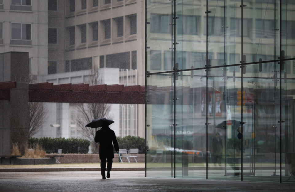 A man carries an umbrella outside of an office building as a light snow falls in Baltimore, Tuesday, March 25, 2014. An unwelcome nor'easter is expected in the region just days after the start of spring. (AP Photo/Patrick Semansky)