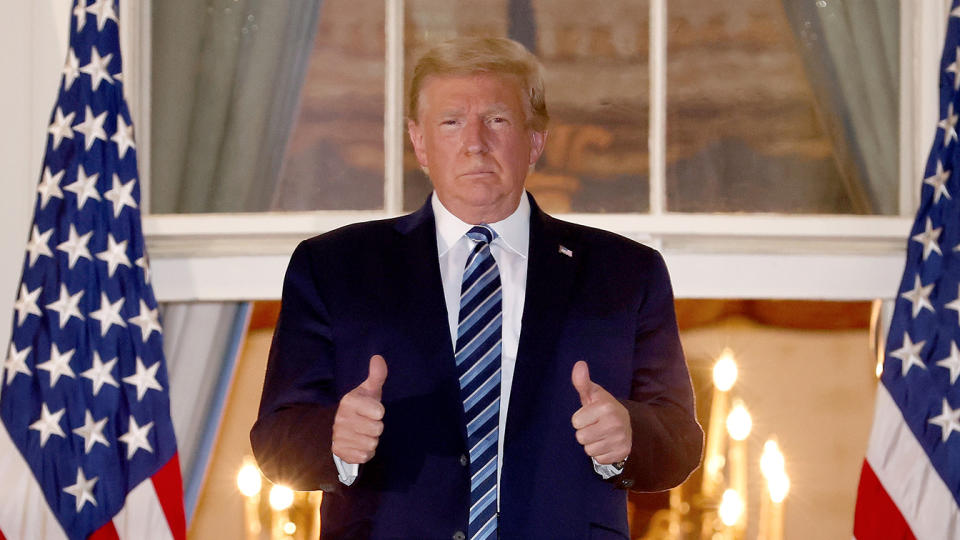 President Trump gives a thumbs up to photographers upon returning to the White House from Walter Reed National Military Medical Center on Monday. (Photo by Win McNamee/Getty Images)
