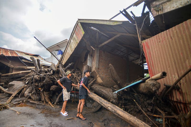 People look at damaged houses affected by heavy rain brought flash floods and landslides in Agam