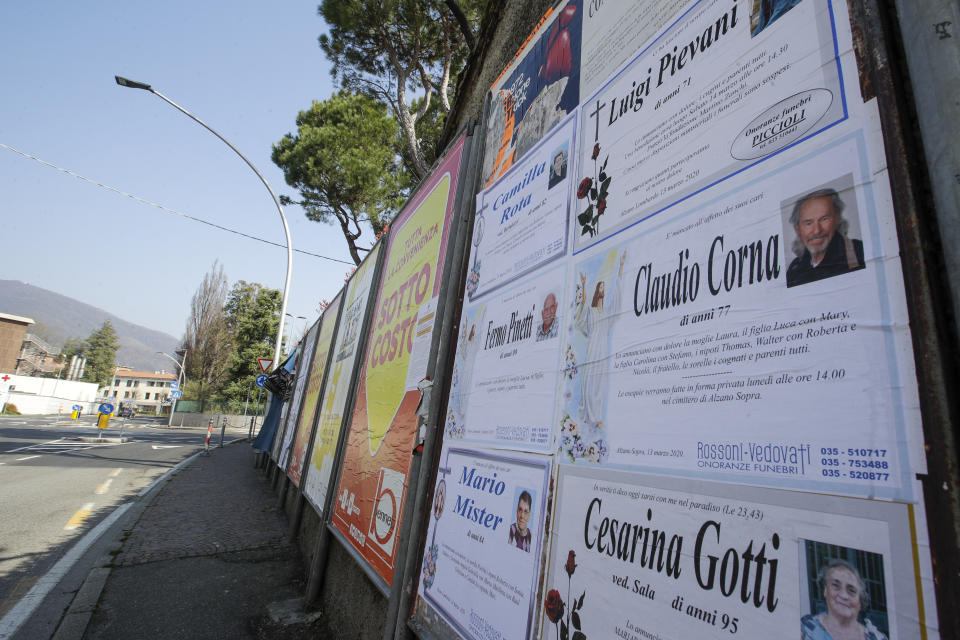 FILE - In this Tuesday, March 17, 2020 filer, death notices are seen on a board along an empty road in Alzano Lombardo, near Bergamo, the heart of the hardest-hit province in Italy's hardest-hit region of Lombardy, Italy, Tuesday, March 17, 2020. As Italy prepares to emerge from the West’s first and most extensive coronavirus lockdown, it is increasingly becoming apparent that something went terribly wrong in Lombardy, the hardest-hit region in Europe’s hardest-hit country. Two days after Italy registered its first positive case in the Lombard town of Codogno, sparking a lockdown of Codogno and nine nearby towns, another positive case was registered Feb. 23 more than an hour’s drive away in the hospital of Alzano Lombardo in the province of Bergamo. Whereas the emergency room of Codogno’s hospital was shuttered after its first positive case, the ER of Alzano’s hospital reopened after a few hours of cleaning, fast becoming one of Bergamo’s main sources of contagion. (AP Photo/Luca Bruno, File)