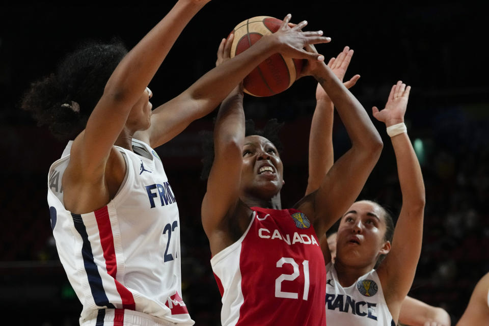 Canada's Nirra Fields, centre, attempts to shoot at goal as France's Marieme Badiane, left, blocks her shot during their game at the women's Basketball World Cup in Sydney, Australia, Friday, Sept. 23, 2022. (AP Photo/Mark Baker)