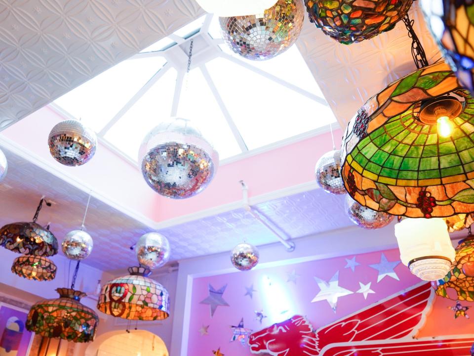 A skylight on a ceiling with Tiffany lamps and disco balls hanging from it.