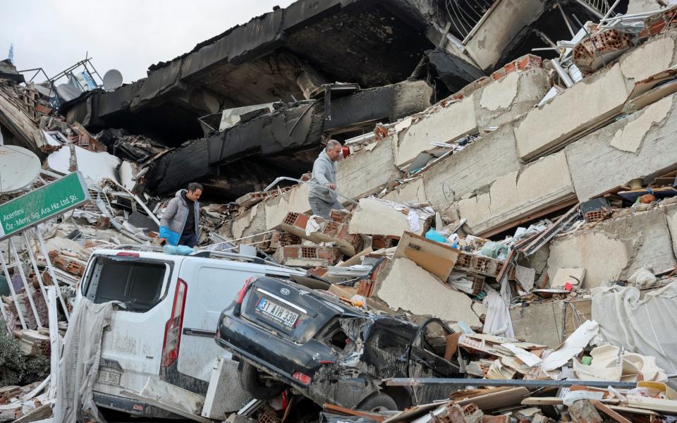 People walk through the rubble of a collapsed building in Hatay - REUTERS/Umit Bektas