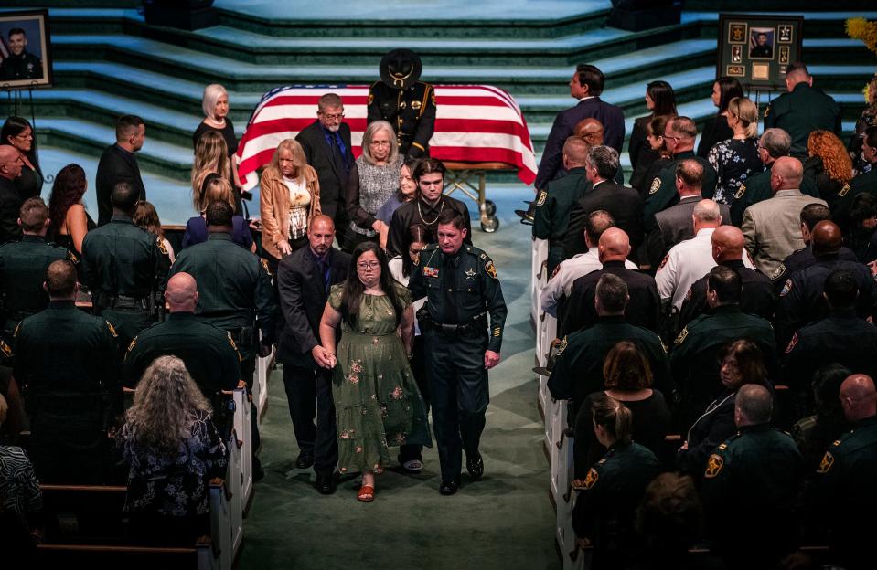 Family members of Deputy Blane Lane exit the service Tuesday at Victory Church in Lakeland.