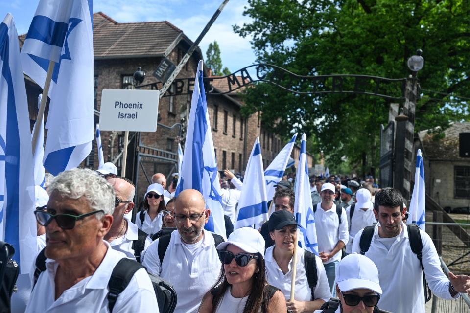 Marchers carry Israeli flags as they walk past the gate to the former Nazi concentration death camp Auschwitz on May 06, 2024, in Oswiecim, Poland. The 36th annual International March of the Living honors the memory of Holocaust victims of World War II.