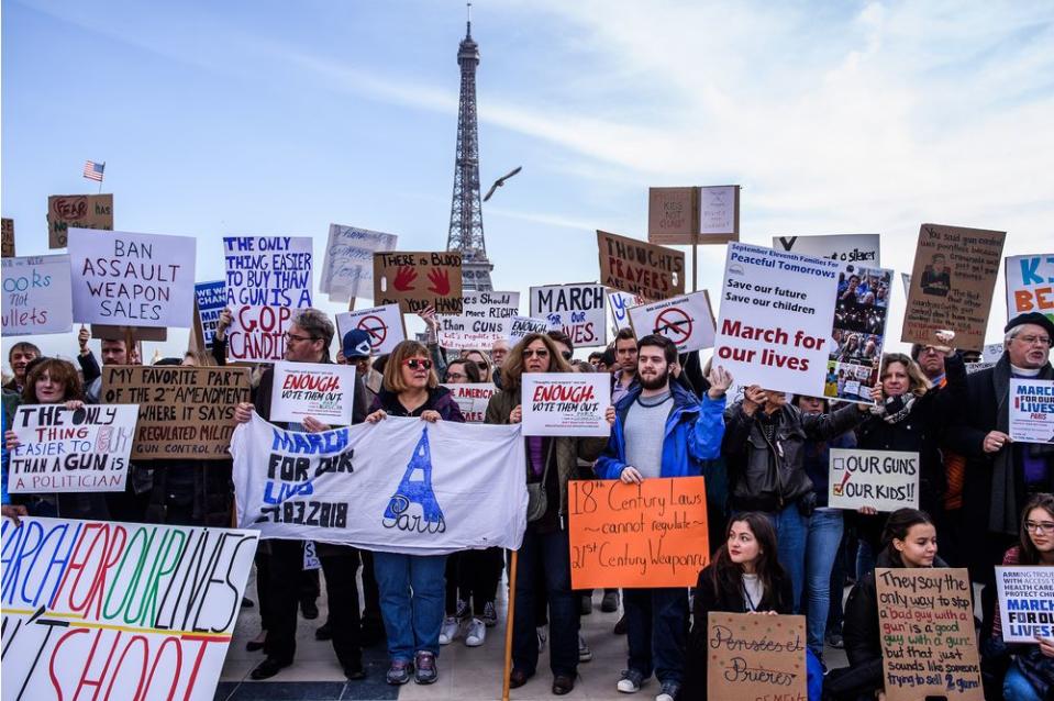 A crowd of French and Americans hold anti-gun posters near the Eiffel Tower.