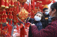 People wear face masks as they shop for decorations for the upcoming Lunar New Year, the Year of the Rat, at a market in Fuyang in central China's Anhui Province, Friday, Jan. 24, 2020. China is swiftly building a hospital dedicated to treating patients infected with a new virus that has killed 26 people, sickened hundreds and prompted unprecedented lockdowns of cities home to millions of people during the country's most important holiday. (Chinatopix via AP)