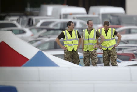Military personnel prepare to work at the site of the airplane crash at the British Car Auctions lot next to Blackbushe Airport, near Camberley in southern Britain August 1, 2015. REUTERS/Luke MacGregor