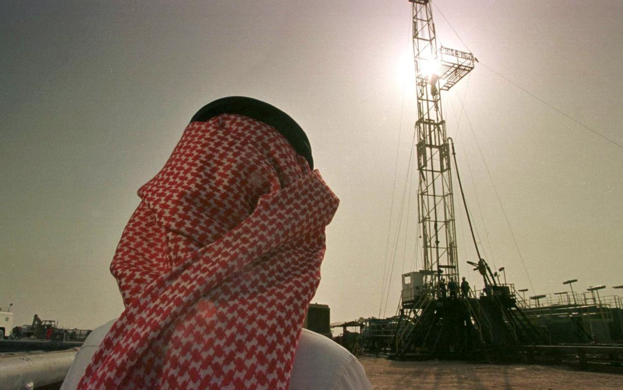 An official of the Saudi oil company Aramco watches progress at a rig at the al-Howta oil field near Howta, Saudi Arabia - JOHN MOORE 