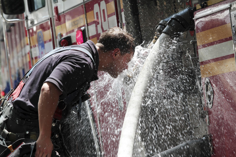 A New York City firefighter cools off on a fire hose after helping extricate a car that fell down an elevator shaft at a garage in Midtown Manhattan, Tuesday, July 17, 2012, in New York. Temperatures are expected to reach into the high 90s Tuesday in the New York metropolitan area. (AP Photo/Mary Altaffer)