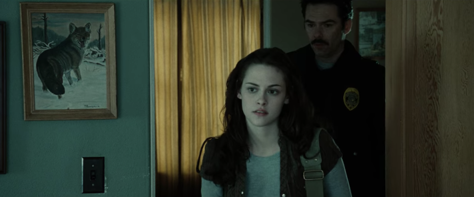 Bella walks into the room, which has a framed picture of a wolf