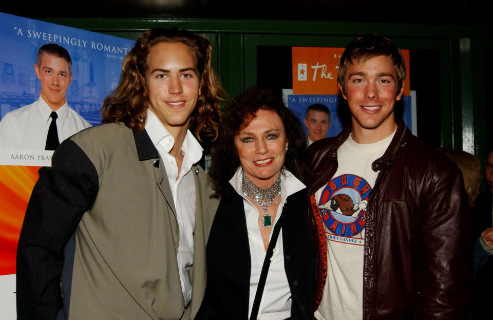 Group of three people with a woman in the middle pose for a picture