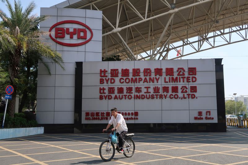 FILE PHOTO: Man cycles past an entrance to the headquarters of Chinese electric car maker BYD in Shenzhen