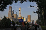 FILE - An evening sunlight casts on a woman as people walk near the Central Business District during the rush hour in Beijing on Monday, Aug. 14, 2023. (AP Photo/Andy Wong, File)