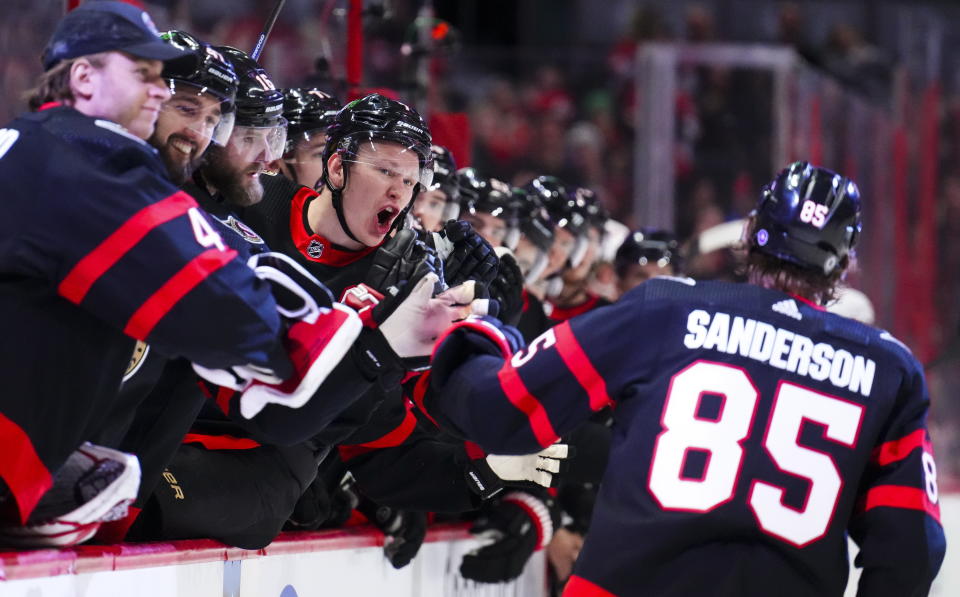 Ottawa Senators left wing Brady Tkachuk (7) shouts at teammate Jake Sanderson (85) who skates past the bench while celebrating his goal against the Detroit Red Wings during second-period NHL hockey game action in Ottawa, Ontario, Monday, Feb. 27, 2023. (Sean Kilpatrick/The Canadian Press via AP)
