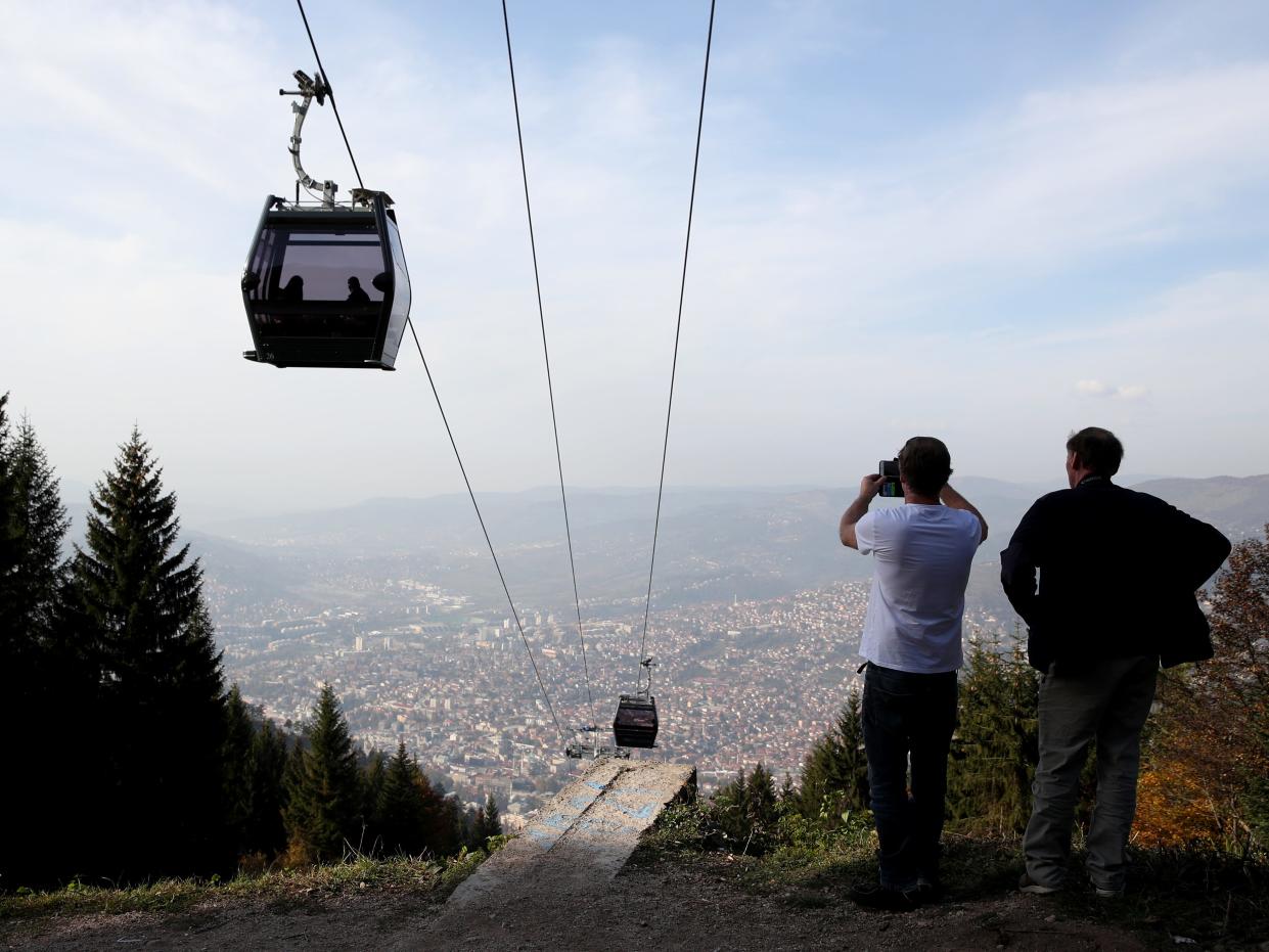 Tourists look at a view of Sarajevo next to the Mount Trebevic cable car in 2018.